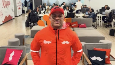 Toguro na sede da Rappi vestindo uniforme da empresa, simbolizando sua chegada como vice-presidente de comunicação e a integração entre criadores de conteúdo e estratégia de marketing digital.